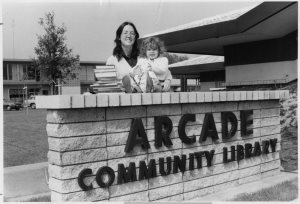 A black and white photo of a woman and child standing near the sign of the Sacramento County Library’s new 12,000-square-foot Arcade Branch at 2443 Marconi Avenue in September 1976.