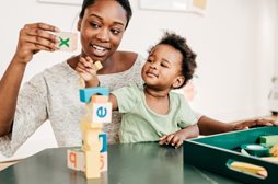 Woman plays with blocks with child.