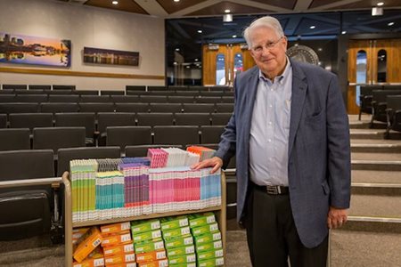 Jim Quillinan next to a cart full of children's books purchased with funds from the Hurst bequest