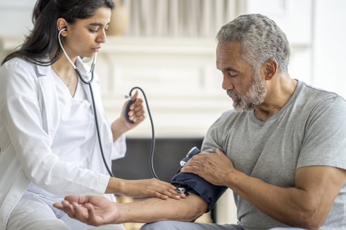 A nurse checks the blood pressure of an adult patient with a blood pressure cuff